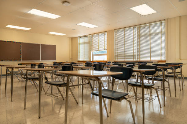 istock Example of an empty nondescript US High School Classroom with desks, Window and black board. 1420229217