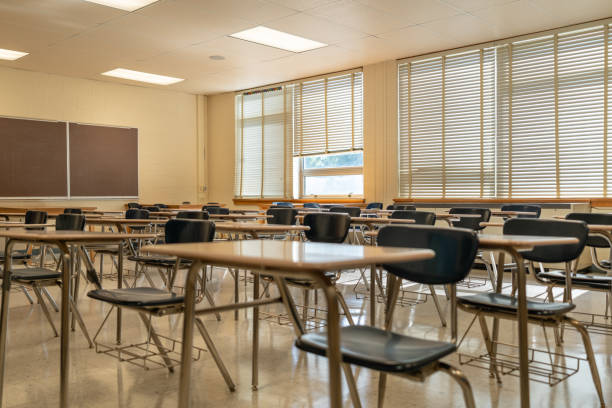 istock Example of an empty nondescript US High School Classroom with desks, Window and black board. 1420229218