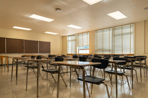 istock Example of an empty nondescript US High School Classroom with desks, Window and black board. 1420229220