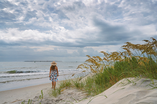 Girl walking by the sand dunes . Fort Macon State Park. Bogue Banks. North Carolina.USA.