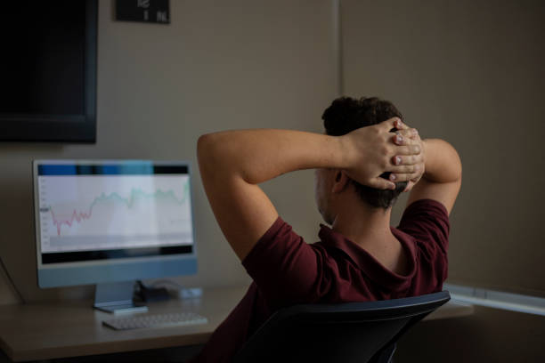 istock Young man looking at stock market on mobile phone and computer screen 1420237676