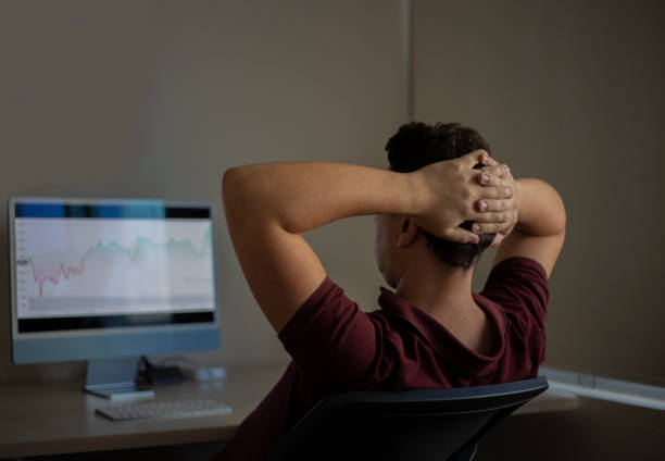 istock Young man looking at stock market on mobile phone and computer screen 1420238404