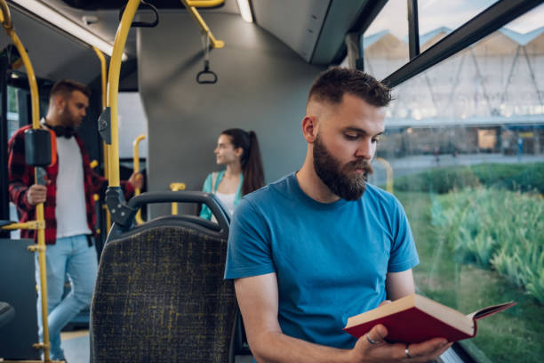 istock Man is riding in a bus and reading a popular fiction book 1420249273