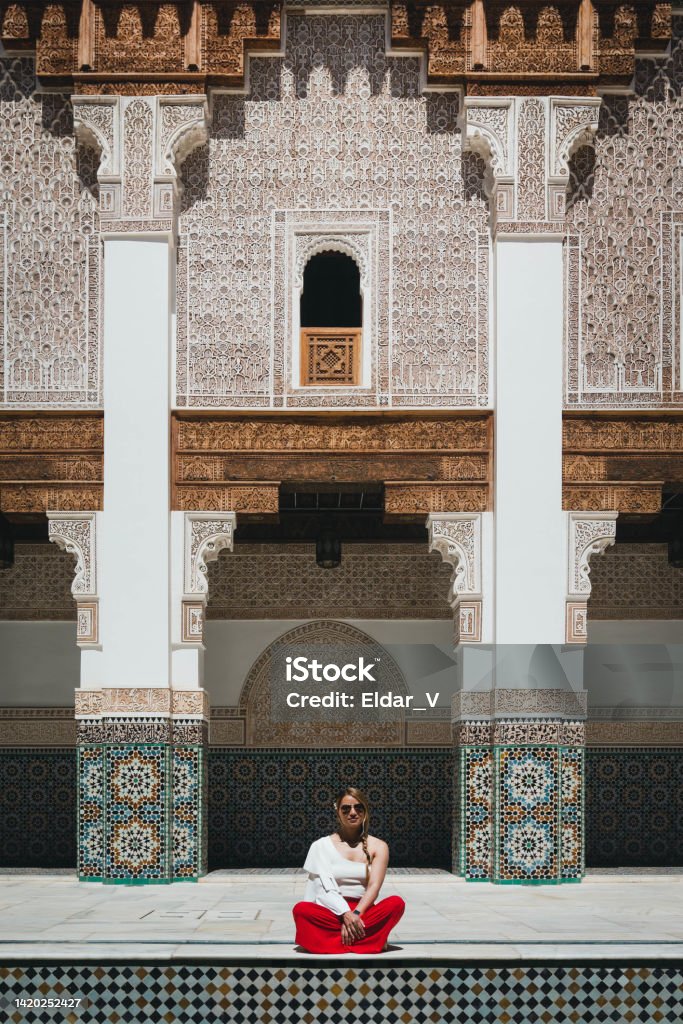 Woman in Moroccan palace young latin woman dressed in a red skirt and a soft blouse, admiring the beauty of the architecture of a Moroccan palace, looking for her inner peace. Morocco Stock Photo