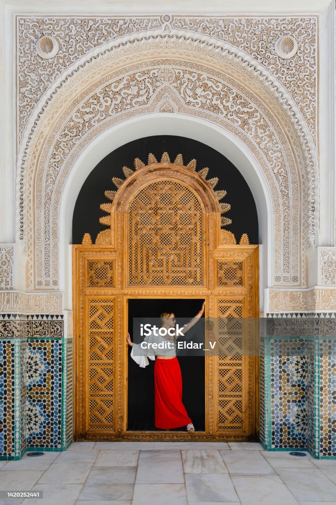 Woman in Moroccan palace young latin woman dressed in a red skirt and a soft blouse, posing in the wooden frame of an ancient Moroccan palace. Morocco Stock Photo