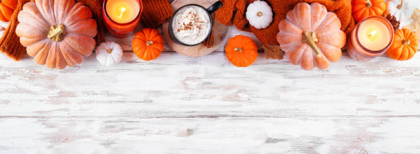 istock Cozy fall top border with pumpkins, leaves, sweater and pumpkin spice drink over a rustic white wood banner background 1420254402
