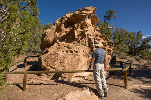In Nevada’s Hickison Petroglyphs Recreation Area, a hiker inspects ancient rock art carved into volcanic tuff known as Great Basin curvilinear style and dates from nearby hunting and living sites to about 10,000 years old.