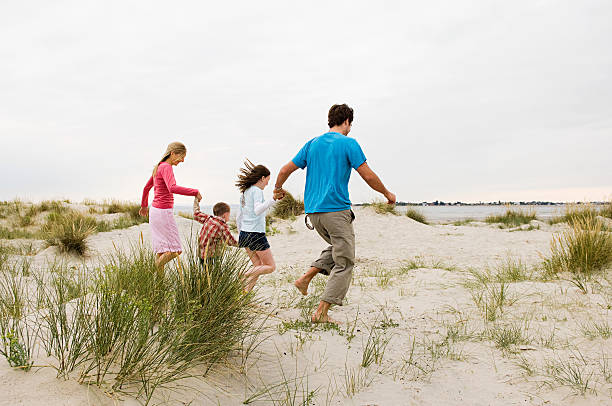 Young family running on beach  chichester stock pictures, royalty-free photos & images