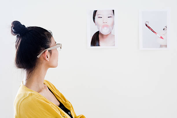 joven diseñadora de moda mirando fotografías en blanco en la pared - chewing gum women bubble blowing fotografías e imágenes de stock