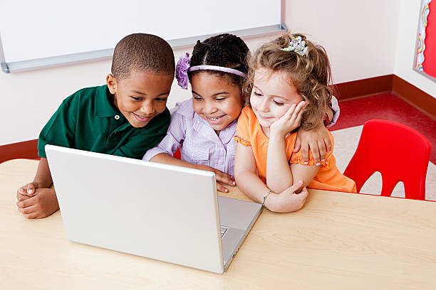 трое детей, глядя на ноутбук вместе - computer student mixed race person multi ethnic group стоковые фото и изображения