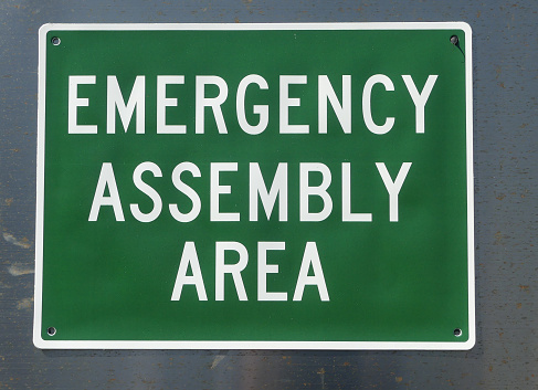 Green Emergency assembly area sign on a building