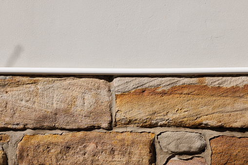 Close-up on an old gray concrete wall on top of sandstone blocks.