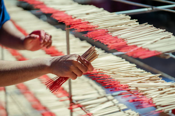 Selective focus. Hand worker working make dried incense stick product on shelf. Southeast asia culture and tourism. Incense sticks SME business.