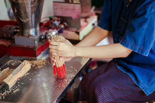 Selective focus. Hand worker indigenous working make dried incense stick product with machine. Southeast asia culture and tourism. Incense sticks SME business.
