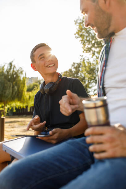 istock Father and son sitting on a park bench, chatting after going home from school 1420303233