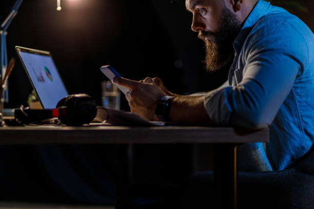 istock Businessman working late at his desk, checking notifications on his smart phone 1420306552