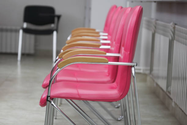 istock Comfortable empty chairs with handles and pink leather upholstery stand in the public auditorium. Lecture hall, library, classroom, lobby or reception area. Selective focus 1420308575
