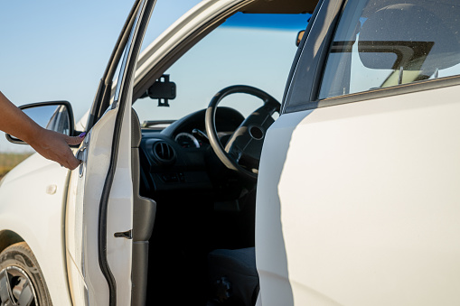 You can see the moment where a hand opens up the door of a white car casting a shadow over it at sunrise.