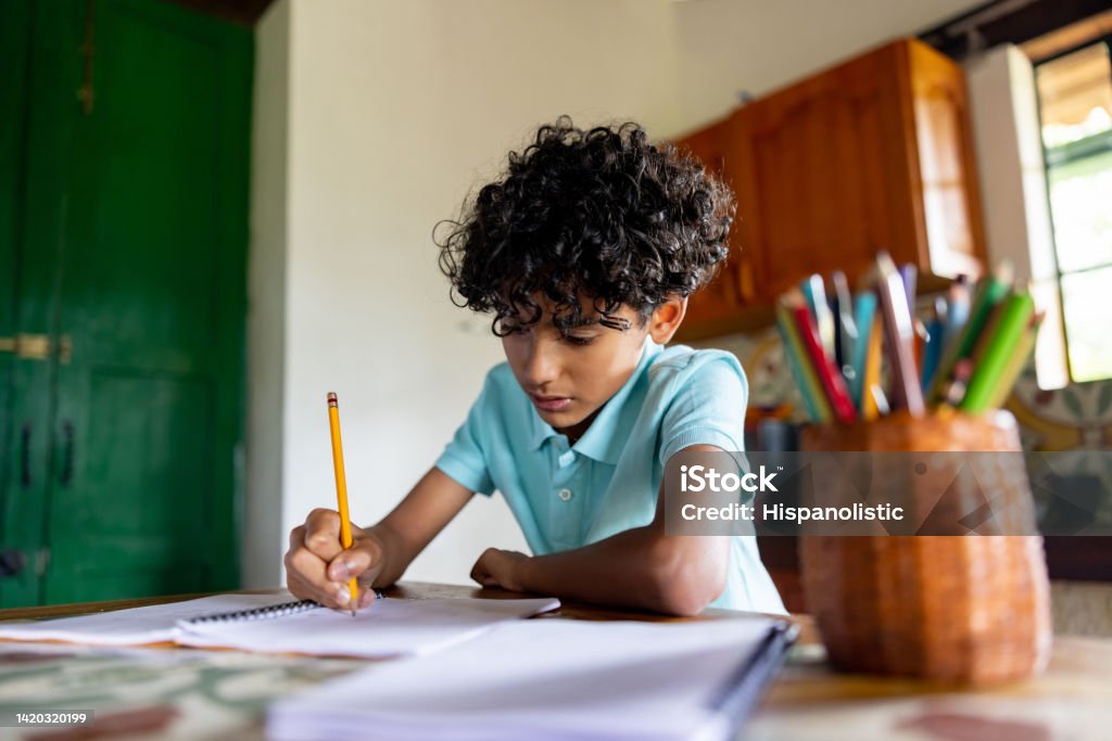 Boy studying at home and doing his homework Latin American boy studying at home looking very focused doing his homework - education concepts Child Stock Photo
