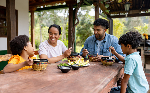 Loving Colombian family eating ajiaco together at home and looking very happy