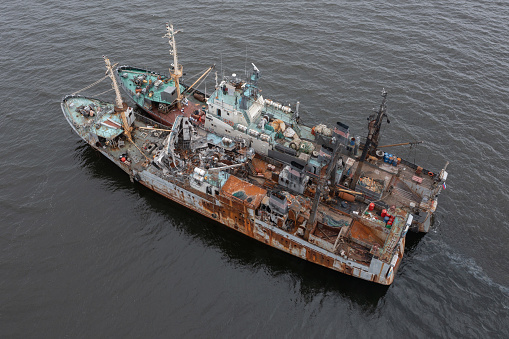 Vladivostok, Russia - July 23, 2022: The burnt fishing vessel on a mooring with other ship.