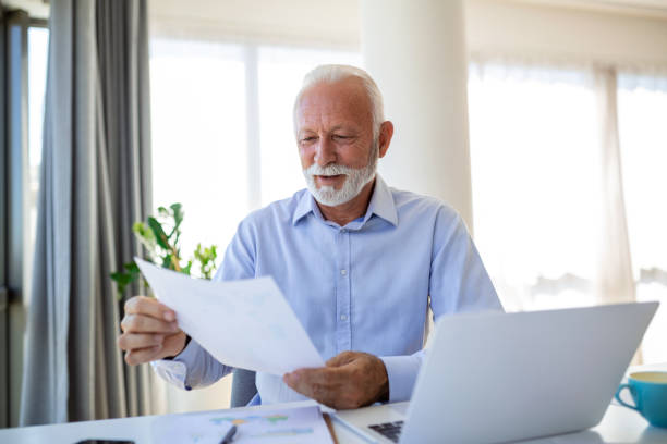 istock Financial advisor businessman using his laptop and doing some paperwork while sitting at desk and working. 1420341748
