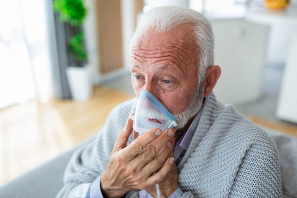 吸入をする病気の老人、薬は最高の薬です。酸素マスクを着用し、covid-19の治療を受けている病気の高齢者。吸入器を持った先輩男性 - oxygen ストックフォトと画像