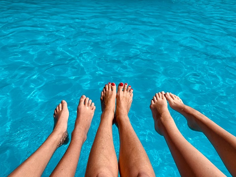Family on vacation. Legs in swimming pool