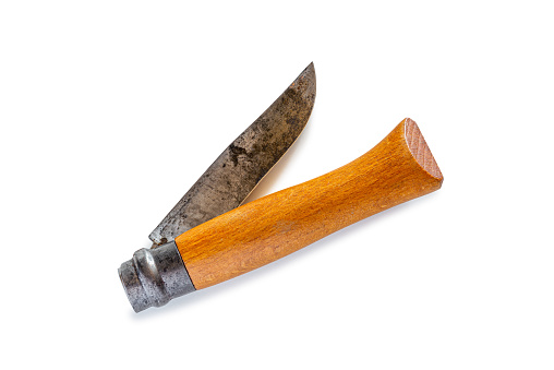 Sharpening stone with a knife and scissors resting on a rustic unpainted wooden table