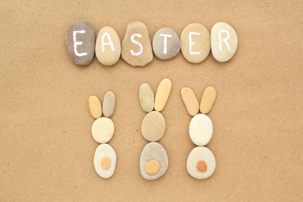 Easter lettering and bunnies from pebbles on craft paper background. Ecological, eco friendly, zero waste, nature concept. Idea for greeting card, poster, banner. Flatlay, lay out, top view