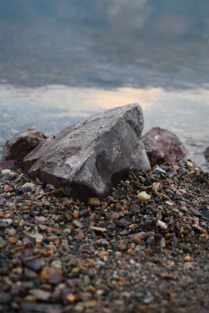 istock Rock and small pebbles on lake shore clear water 1420377100