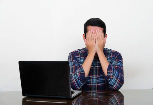 asian man cover his face with hand when sitting in his working table - pusing imagens e fotografias de stock