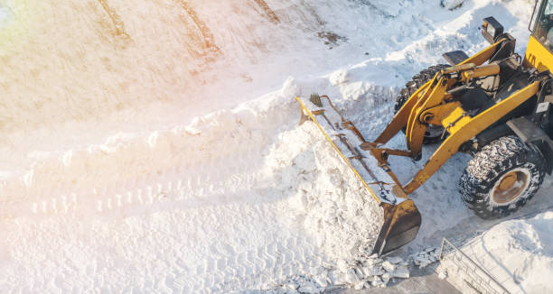 duży pomarańczowy ciągnik usuwa śnieg z drogi i oczyszcza chodnik - clear sky construction vehicle bulldozer commercial land vehicle zdjęcia i obrazy z banku zdjęć