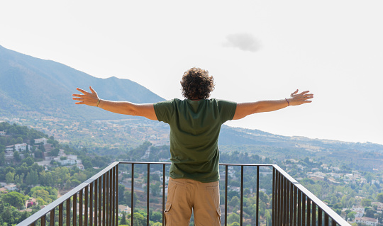 Man with open arms in concept of freedom looking at mountains