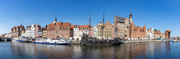 Gdansk, Poland - August 13, 2022: A picture of some Gdansk landmarks next to the river Motlawa, such as the Crane (far right), the St. Mary's Gate (right), the Black Pearl ship (center), and the Chlebnicka Gate (left).