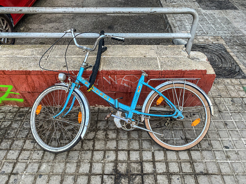 Valencia, Spain - August 15, 2022: High angle view of Peugeot bike attached to railing in the street. More and more people use bicycles as a mode of transport and leave them in the street while not using them