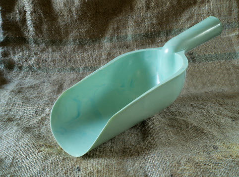 Top view close up of a light blue cast iron cooking pot and a wooden spoon on white background