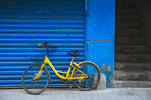 Old vintage yellow bicycle parked by the blue wall shop shutters in Xian town, Shaanxi Province, China