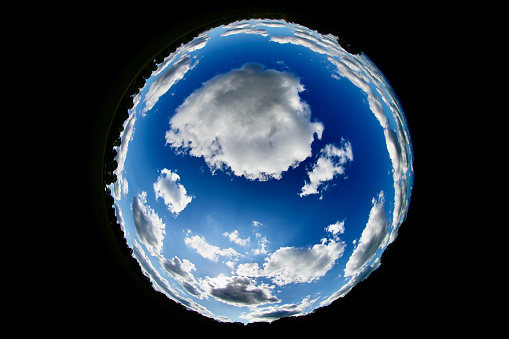 A circular image of the sky with cloudscape, a globe in a globe