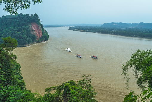Three sightseeing boats with tourists sailing on the Min River and Dadu River in Leshan, as seen from the scenic lookout located above the Giant Budda, the southern part of Sichuan province, China
