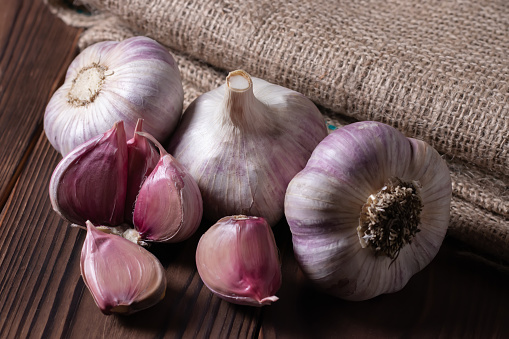 Garlic bulb on wooden background and sackcloth. Close up,