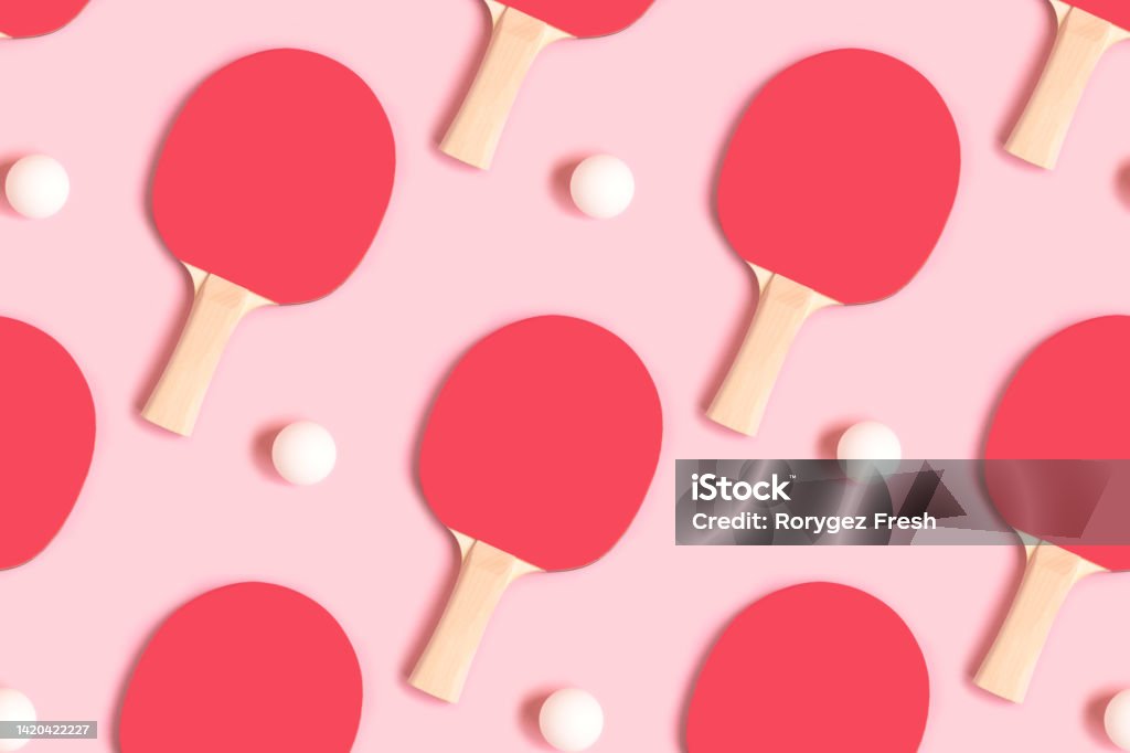Repetitive pattern made of tennis racket and white ball. Repetitive pattern made of tennis racket and white ball on a pink pastel background. Creative layout. Table Tennis Stock Photo