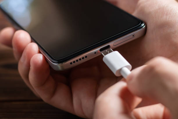 istock Man hands plugging a charger in a smart phone. 1420424832