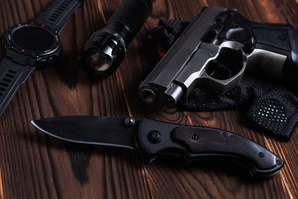 istock Folding pocket knife with pistol and flashlight on wooden background 1420425077