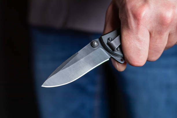 istock Closeup male hand holds sharp knife against black background 1420425743