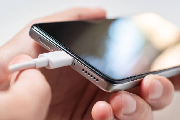istock Man hands plugging a charger in a smart phone. 1420425766