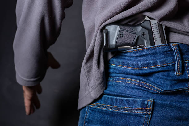istock Problems of terrorism and the unauthorized application of shooting iron. Person holds hide a handgun behind a back. 1420425767