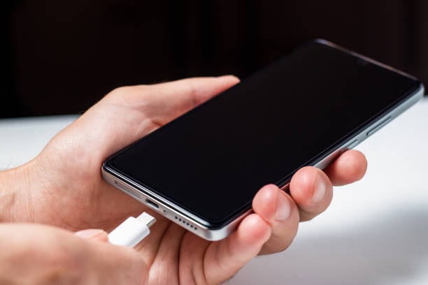 istock Man hands plugging a charger in a smart phone. Man using smartphone with powerbank. 1420425800