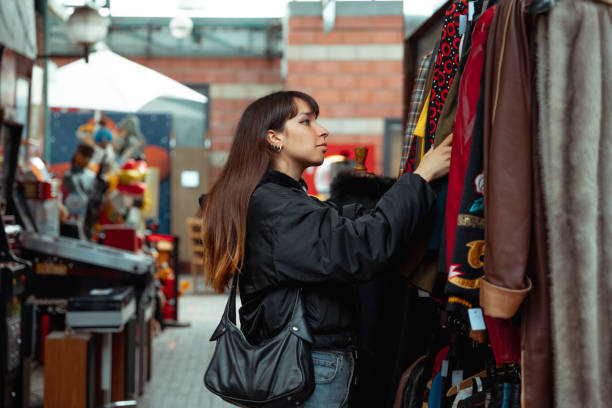 mujer joven comprando ropa vintage - flea market fotografías e imágenes de stock