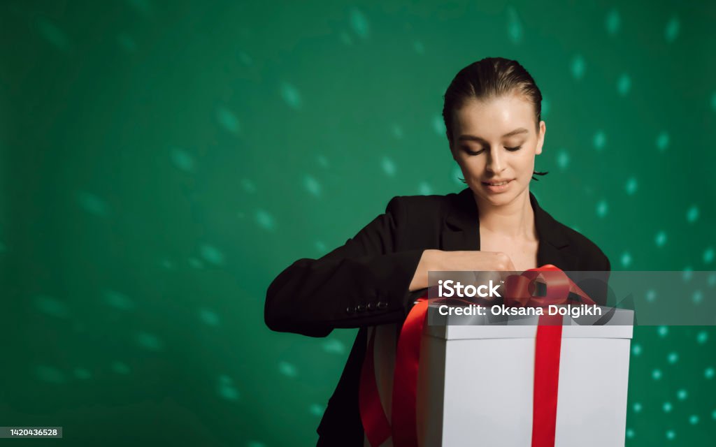 Holidays, celebration and women concept. Portrait of happy charismatic blond girl  With gift box wondering what's inside,  celebrating birthday, receive b-day presents, green background 20-24 Years Stock Photo